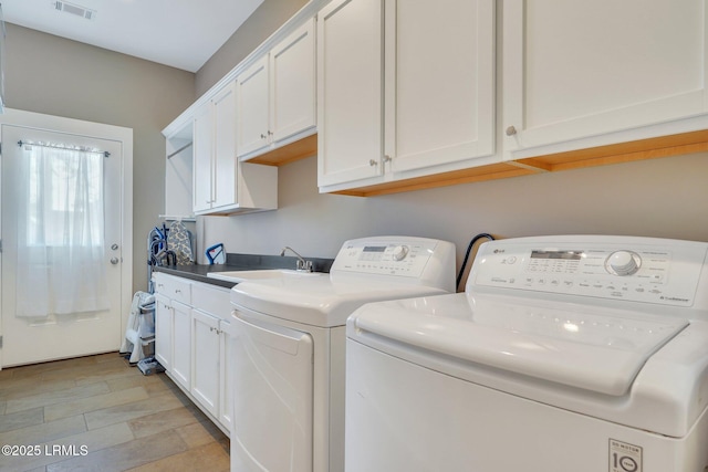 clothes washing area with visible vents, washer and clothes dryer, a sink, and cabinet space