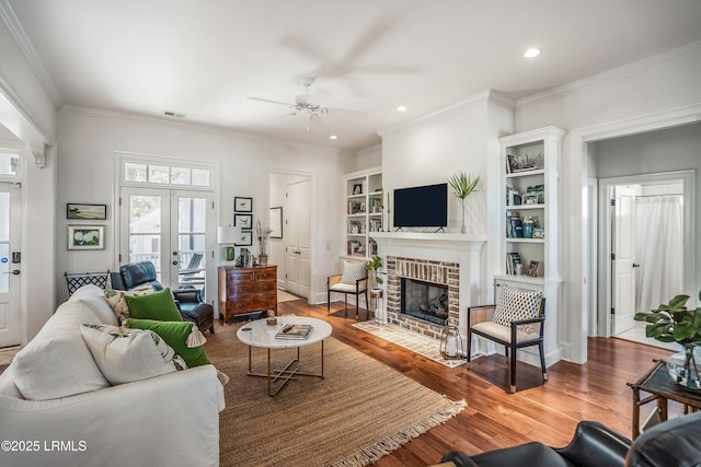 living room featuring hardwood / wood-style floors, a fireplace, ornamental molding, and french doors