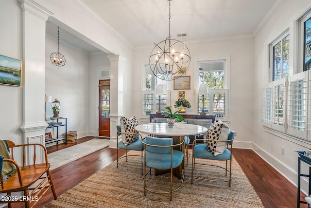 dining room with decorative columns, dark hardwood / wood-style flooring, ornamental molding, and an inviting chandelier