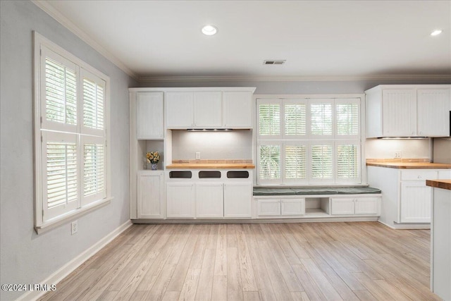 kitchen with white cabinetry, crown molding, light hardwood / wood-style floors, and butcher block countertops