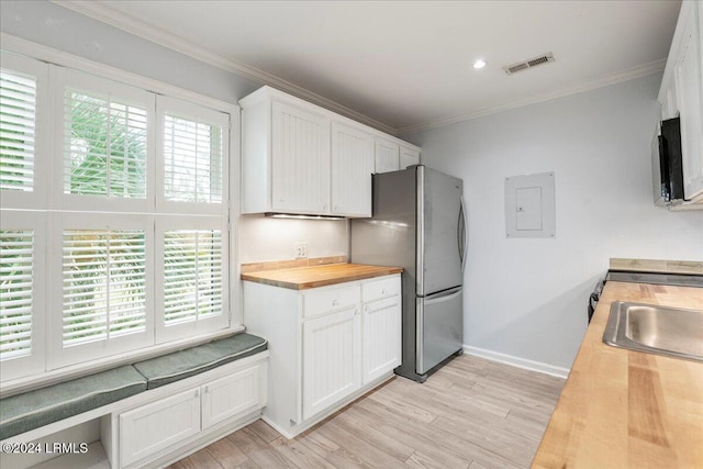 kitchen featuring butcher block countertops, stainless steel fridge, ornamental molding, and white cabinets