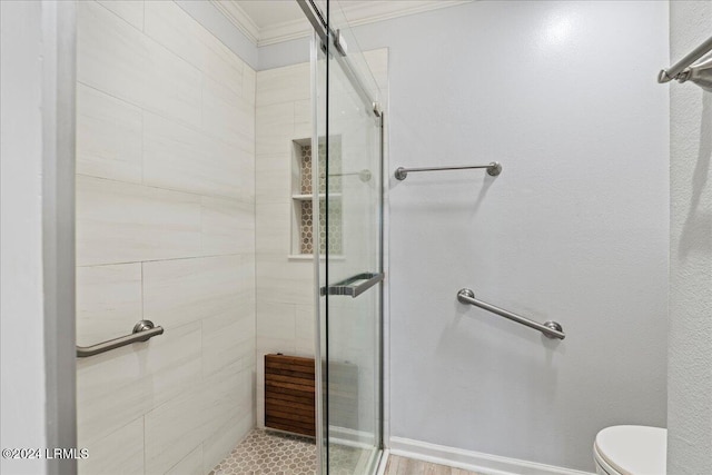 bathroom with tiled shower, ornamental molding, and toilet