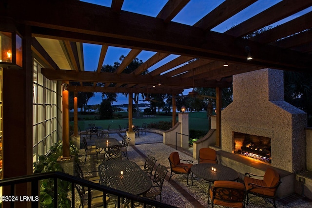 patio terrace at dusk with a pergola and an outdoor fireplace