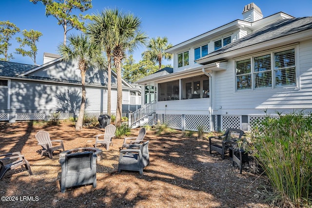 rear view of house with a sunroom and an outdoor fire pit