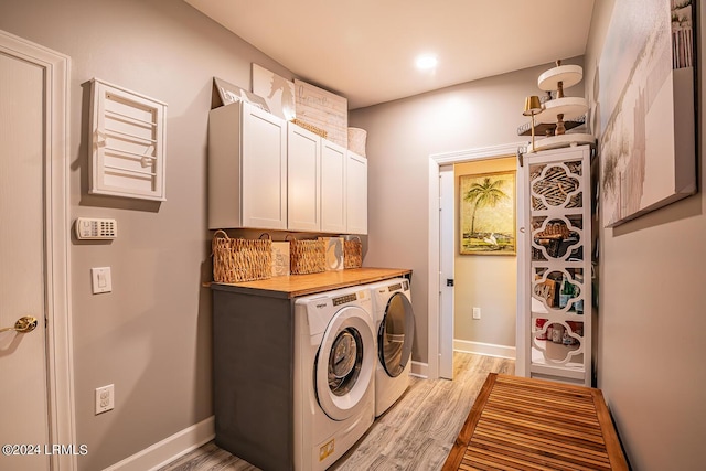 washroom featuring cabinets, separate washer and dryer, and light hardwood / wood-style floors