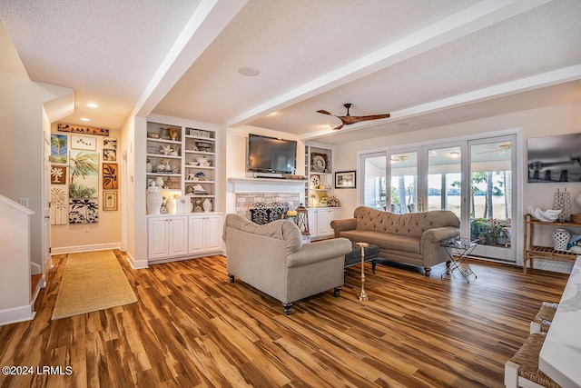 living room with built in features, ceiling fan, hardwood / wood-style floors, a textured ceiling, and beamed ceiling