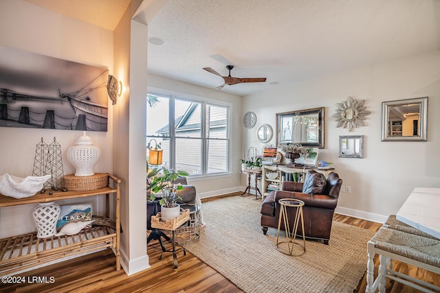 living area with hardwood / wood-style flooring, a textured ceiling, and ceiling fan