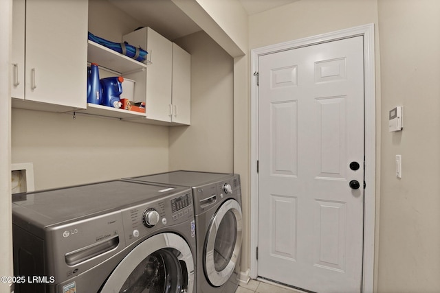 washroom featuring washing machine and clothes dryer, light tile patterned flooring, and cabinet space
