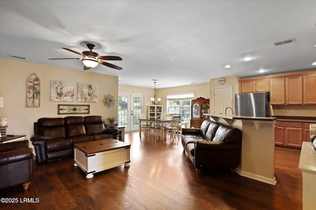 living area featuring visible vents, recessed lighting, dark wood-style flooring, and ceiling fan with notable chandelier