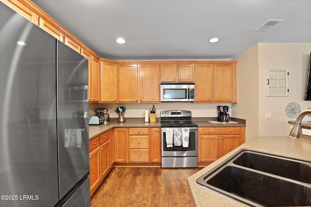 kitchen with visible vents, appliances with stainless steel finishes, dark wood finished floors, a sink, and recessed lighting