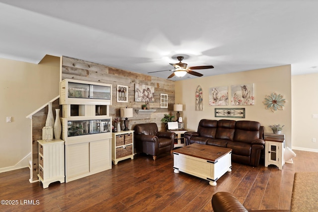 living area featuring baseboards, a ceiling fan, and dark wood-type flooring