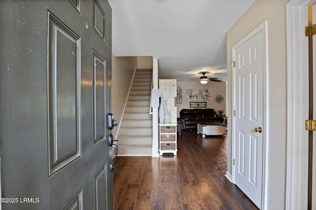 foyer entrance with baseboards, a ceiling fan, dark wood finished floors, and stairs