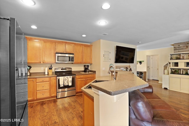 kitchen featuring appliances with stainless steel finishes, a sink, dark wood finished floors, recessed lighting, and open floor plan