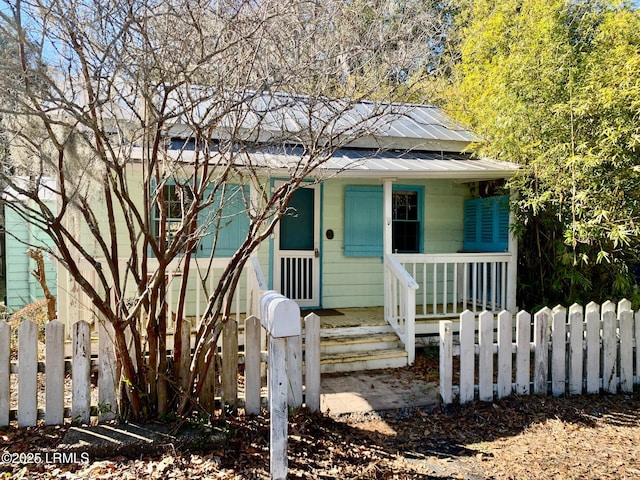 bungalow-style home with a porch, metal roof, and a fenced front yard