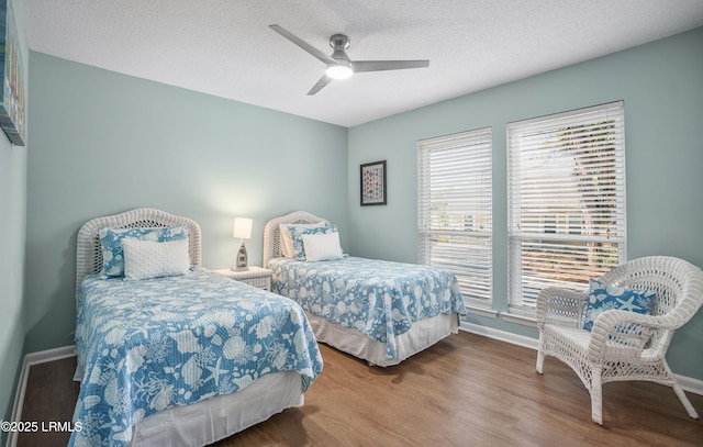 bedroom with ceiling fan, a textured ceiling, baseboards, and wood finished floors