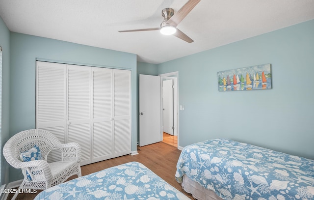 bedroom featuring ceiling fan, a closet, baseboards, and wood finished floors
