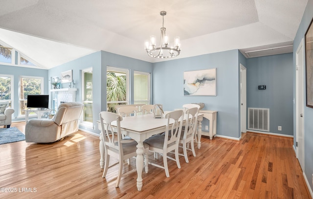 dining space featuring visible vents, baseboards, lofted ceiling, light wood-style flooring, and a chandelier