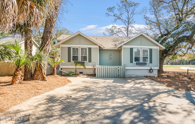 view of front of home with roof with shingles, a fenced front yard, and a gate