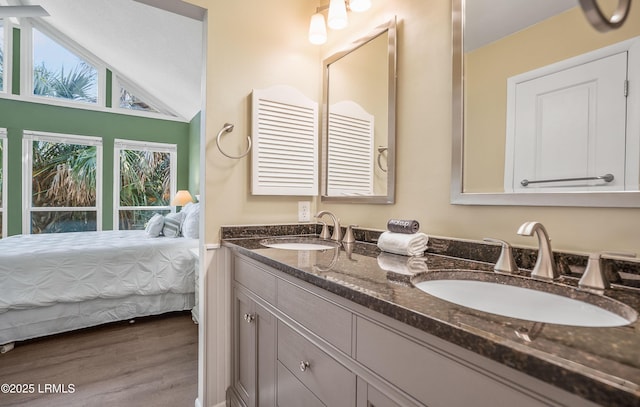 bathroom featuring lofted ceiling, a sink, ensuite bath, and wood finished floors