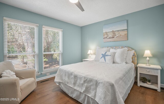 bedroom with visible vents, a ceiling fan, a textured ceiling, wood finished floors, and baseboards