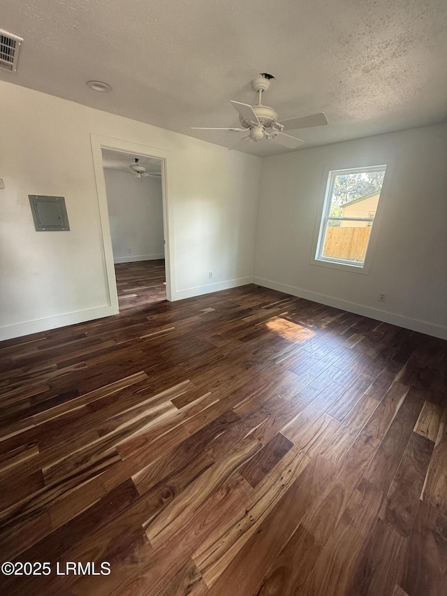 spare room with a textured ceiling, ceiling fan, dark wood finished floors, and baseboards