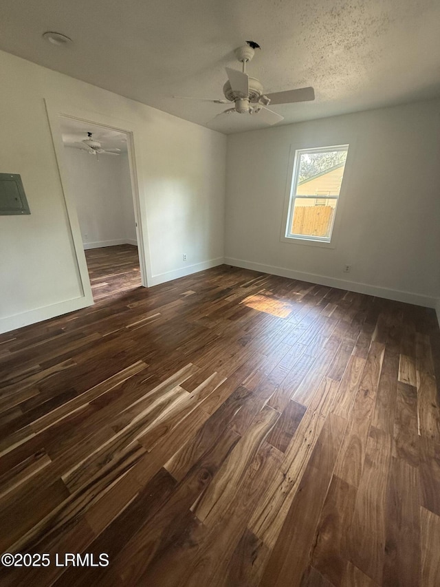 empty room featuring dark wood finished floors, a ceiling fan, and baseboards