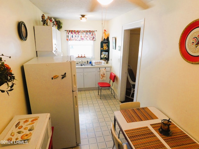 kitchen with white cabinetry, sink, and white fridge