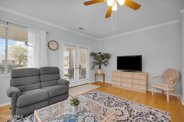 living area with light wood-style floors, a wealth of natural light, crown molding, and baseboards