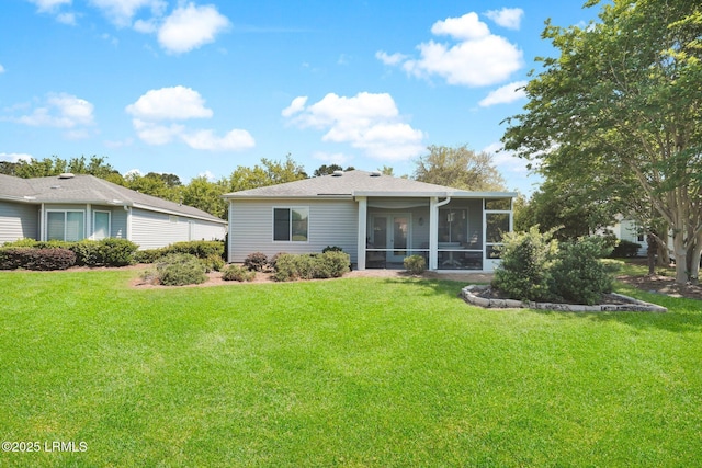 back of property with a lawn, a shingled roof, and a sunroom