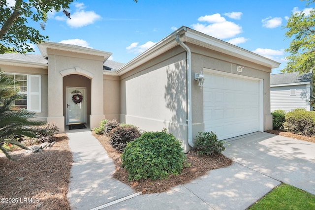 mediterranean / spanish home featuring an attached garage, concrete driveway, stucco siding, and roof with shingles