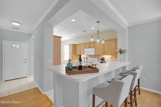 kitchen with decorative backsplash, a kitchen breakfast bar, white appliances, and crown molding