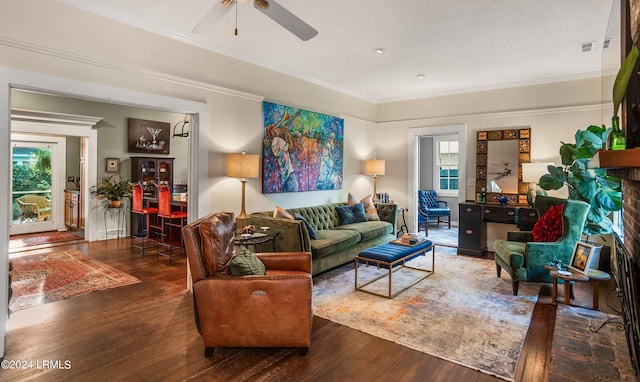 living room with ornamental molding, dark wood-type flooring, and ceiling fan