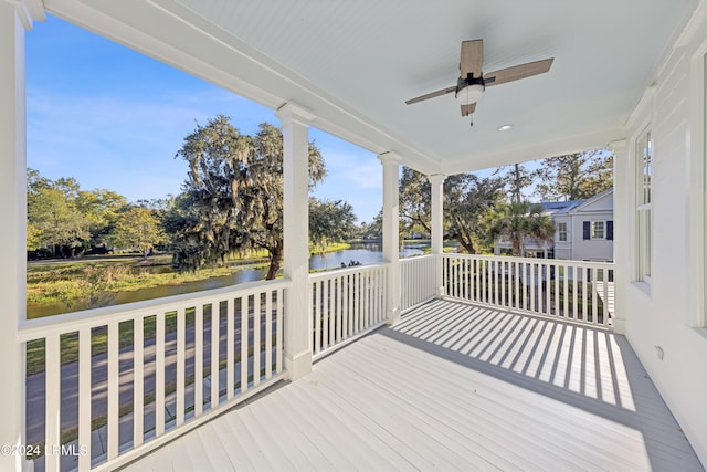 wooden deck with a water view and ceiling fan