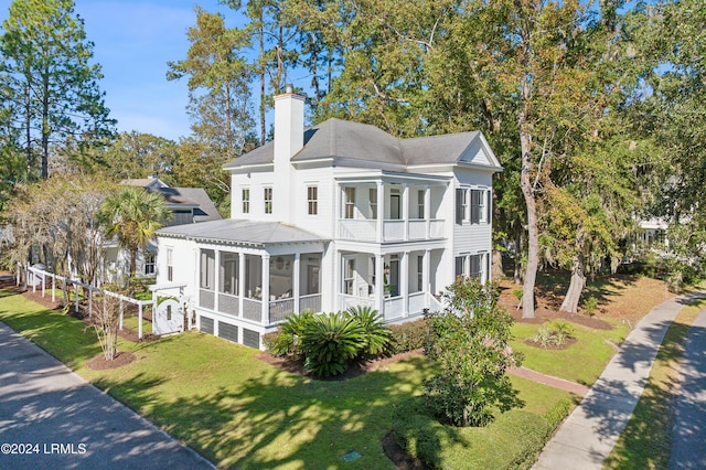 exterior space featuring a balcony, a yard, and a sunroom