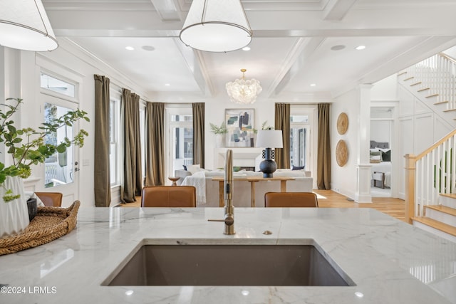 kitchen featuring light stone counters, sink, plenty of natural light, and hanging light fixtures