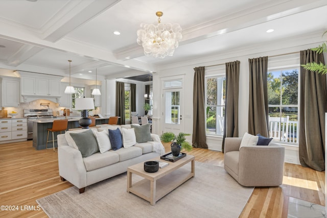 living room with an inviting chandelier, ornamental molding, beamed ceiling, and light wood-type flooring