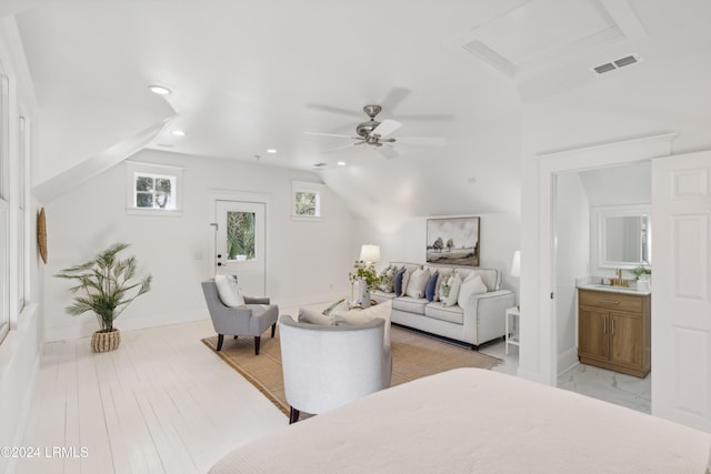 bedroom featuring ceiling fan, lofted ceiling, ensuite bath, and light wood-type flooring