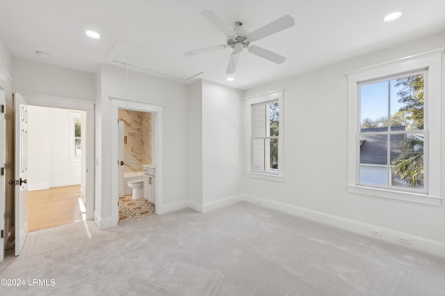 unfurnished bedroom with ceiling fan, light carpet, and ensuite bath