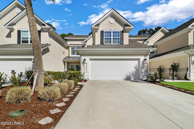 traditional home with concrete driveway, fence, an attached garage, and stucco siding