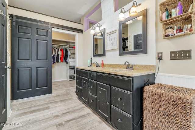 618 Dolphin Anx, Fripp Island, SC 29920 - bathroom with double vanity, wood finished floors, a spacious closet, and wainscoting