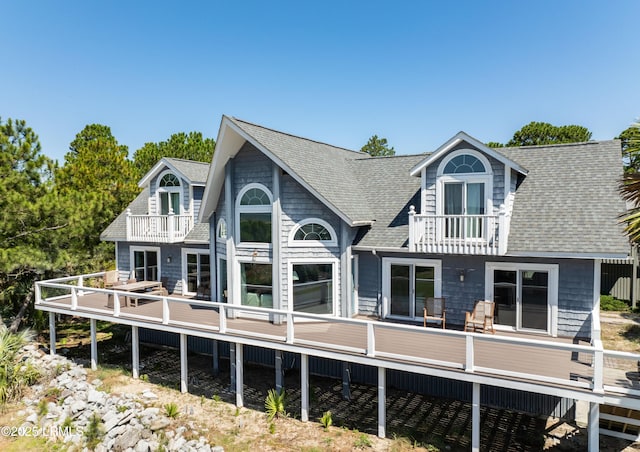 rear view of property featuring a shingled roof and a balcony