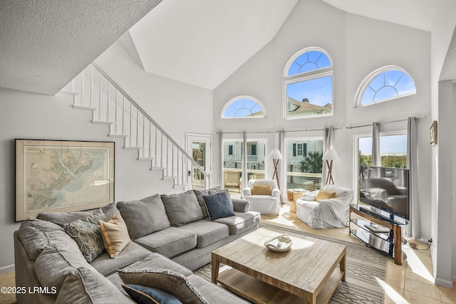 living room with light tile patterned floors, high vaulted ceiling, and stairway