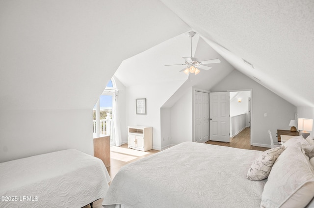 bedroom featuring light wood-style floors, a ceiling fan, vaulted ceiling, a textured ceiling, and baseboards