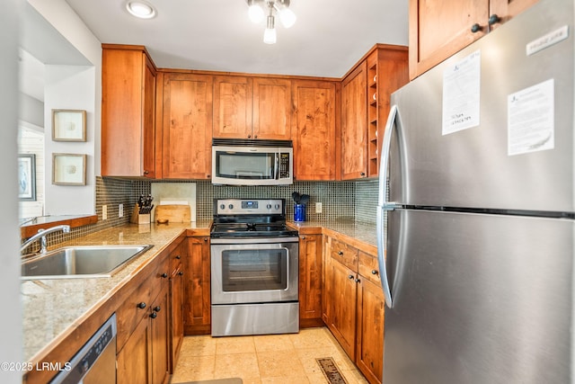 kitchen featuring stainless steel appliances, brown cabinets, a sink, and decorative backsplash