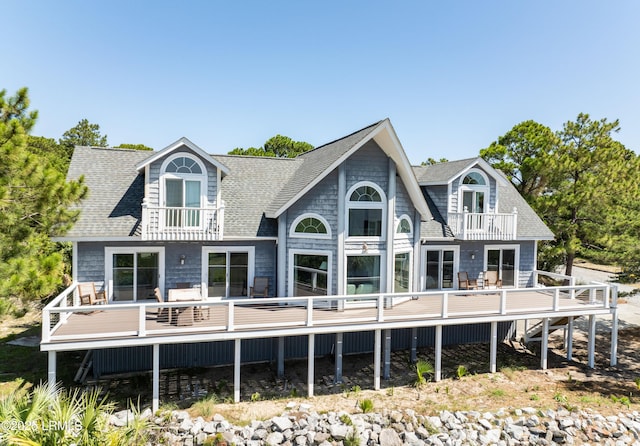 back of house featuring roof with shingles and a balcony