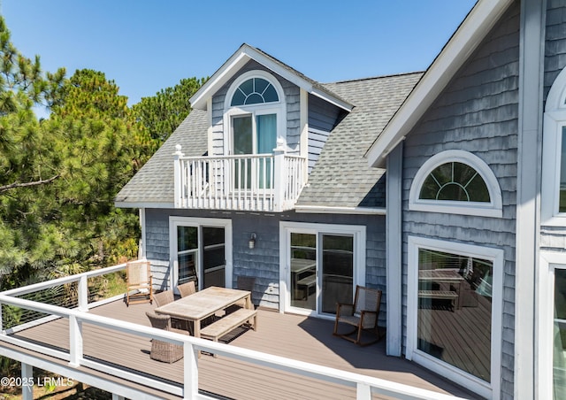 rear view of house with a shingled roof and a balcony