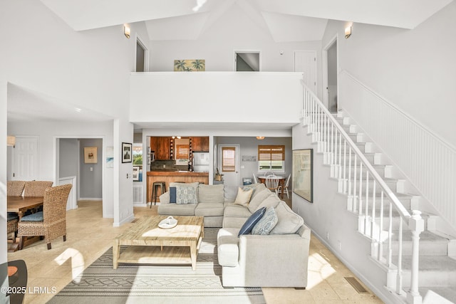 living room with a towering ceiling, baseboards, stairs, and visible vents