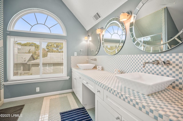 bathroom with vaulted ceiling, tile patterned flooring, a sink, and visible vents