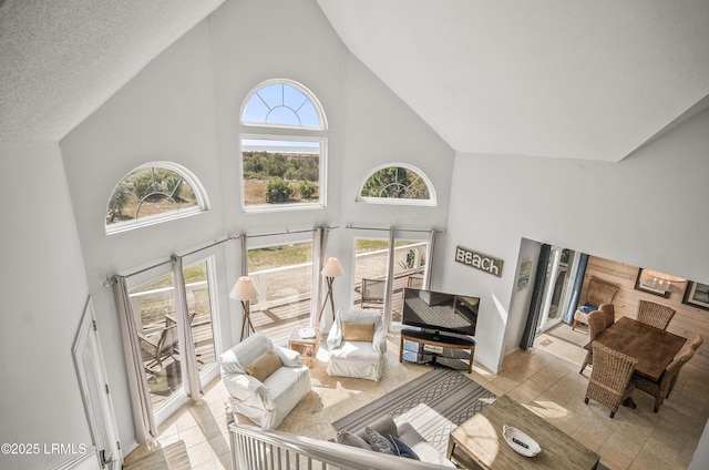 living area with high vaulted ceiling and a textured ceiling