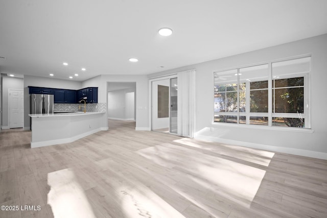 unfurnished living room with sink and light hardwood / wood-style floors